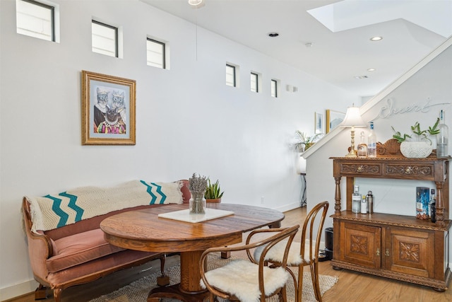 dining room with a skylight, light wood-type flooring, recessed lighting, and baseboards