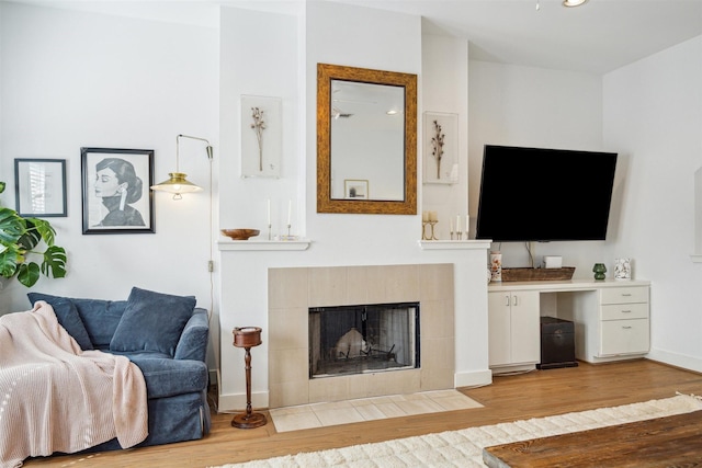 living area with light wood-type flooring, a fireplace, and baseboards