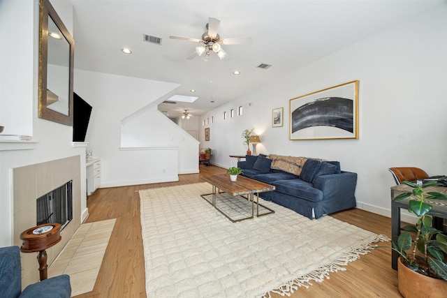 living room with visible vents, baseboards, wood finished floors, and ceiling fan