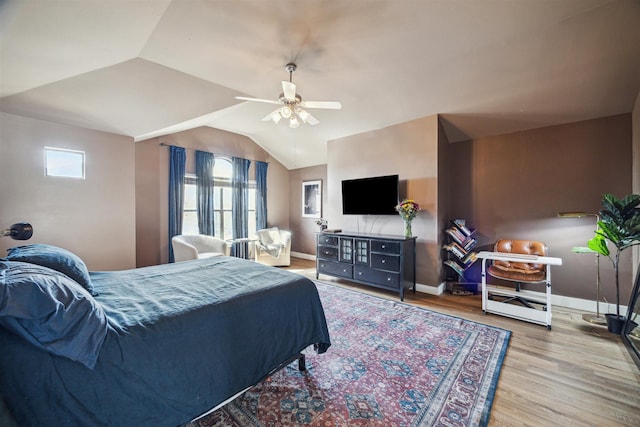 bedroom featuring wood finished floors, baseboards, a ceiling fan, and lofted ceiling