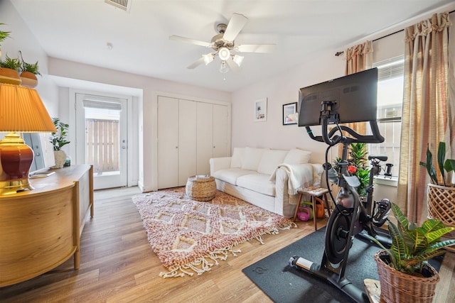 living room with light wood finished floors, a ceiling fan, and visible vents