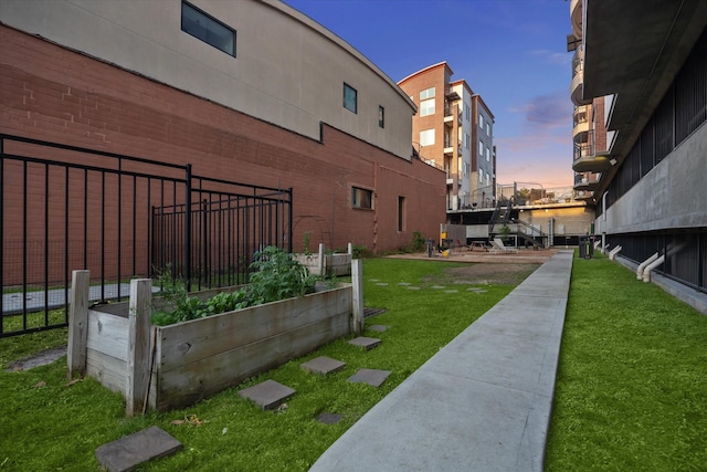 view of community with fence, a lawn, and a vegetable garden