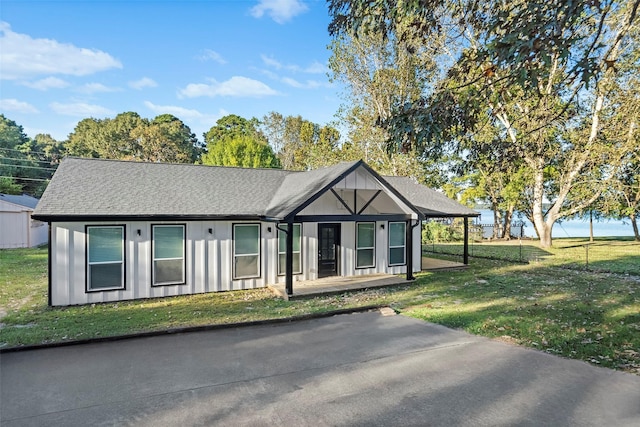 view of front of property featuring roof with shingles, board and batten siding, and a front lawn