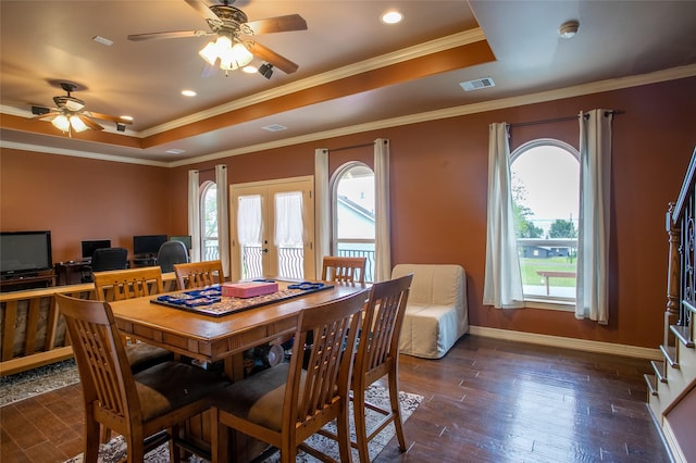 dining area with wood-type flooring, a raised ceiling, plenty of natural light, and a ceiling fan