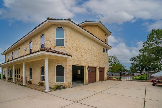 view of front of property featuring an attached garage, driveway, fence, and stone siding
