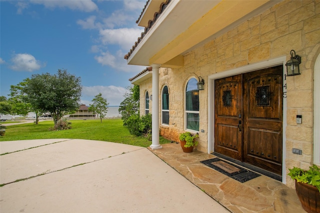 view of exterior entry featuring a yard and stone siding