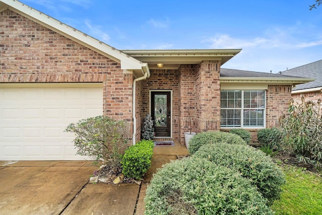 entrance to property with an attached garage, driveway, and brick siding