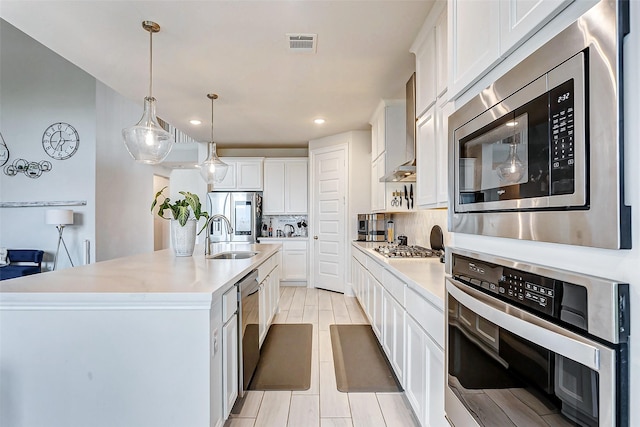 21123 Coral View Dr, Cypress, TX 77433 - kitchen with white cabinets, visible vents, a sink, stainless steel appliances, and backsplash