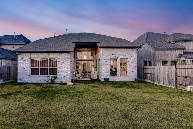 21123 Coral View Dr, Cypress, TX 77433 - back of property at dusk featuring brick siding, a fenced backyard, and a lawn