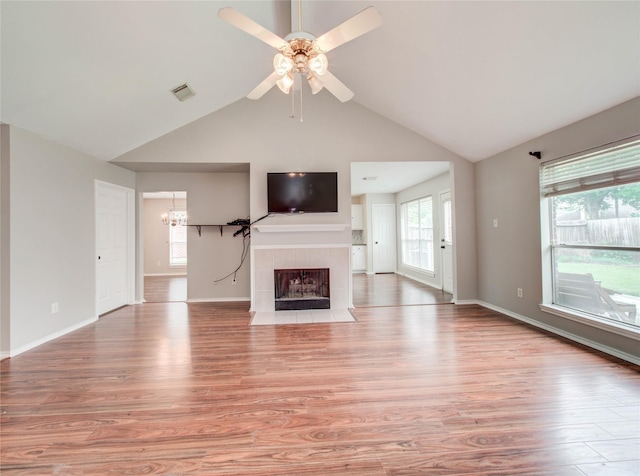 1311 Holly Lake Ct, Katy, TX 77450 - unfurnished living room with vaulted ceiling, ceiling fan with notable chandelier, light wood finished floors, a fireplace, and visible vents