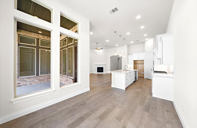 8215 Mount Washburn Ln, Porter, TX 77365 - kitchen with visible vents, white cabinets, a sink, open floor plan, and an island with sink