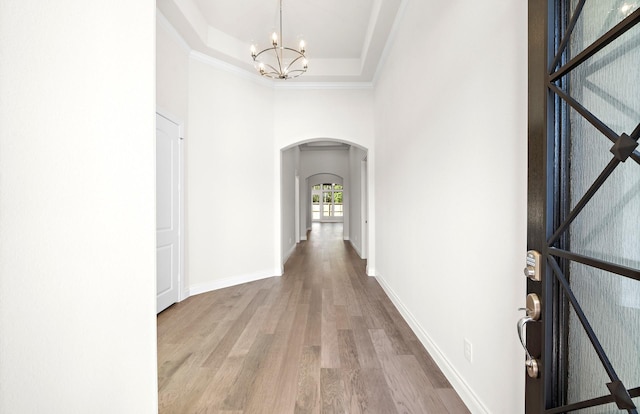 8215 Mount Washburn Ln, Porter, TX 77365 - foyer entrance with baseboards, a raised ceiling, arched walkways, an inviting chandelier, and wood finished floors