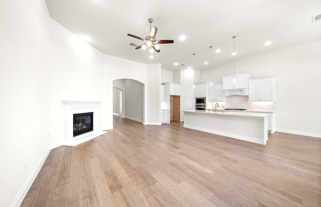 8215 Mount Washburn Ln, Porter, TX 77365 - unfurnished living room with baseboards, arched walkways, a sink, light wood-type flooring, and a ceiling fan