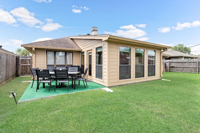 back of property with roof with shingles, a chimney, a patio area, a fenced backyard, and a yard