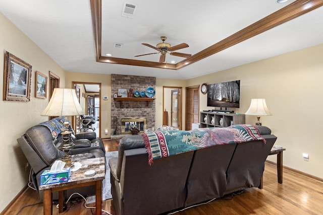living area with visible vents, baseboards, a ceiling fan, and wood finished floors