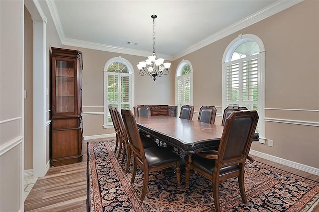 dining area featuring light wood finished floors, a notable chandelier, visible vents, and crown molding
