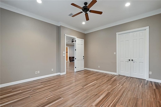 unfurnished bedroom with baseboards, ornamental molding, recessed lighting, visible vents, and wood finished floors