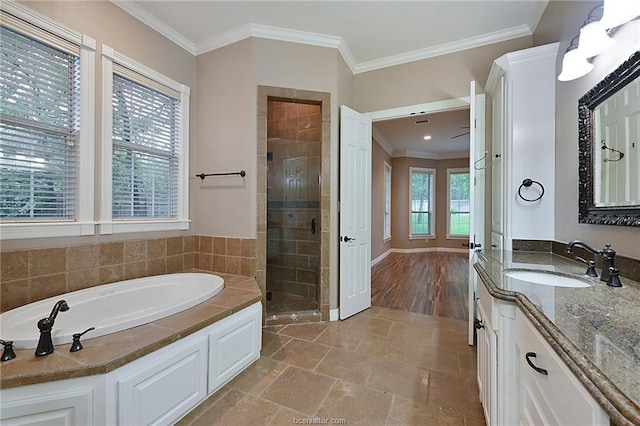 bathroom with crown molding, a garden tub, vanity, a stall shower, and baseboards