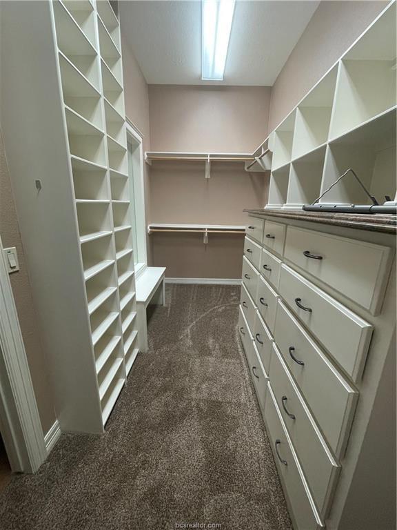 walk in closet featuring dark carpet