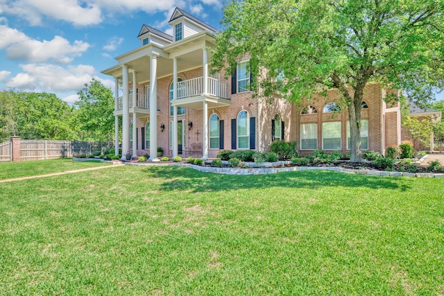 view of front of house with brick siding, a front lawn, fence, and a balcony