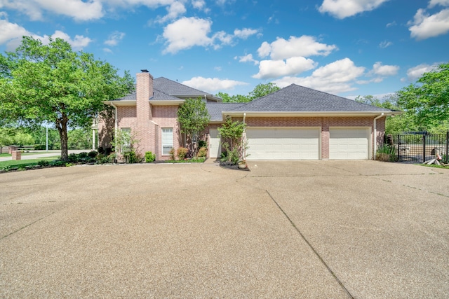 view of front of home featuring concrete driveway, a chimney, an attached garage, brick siding, and fence