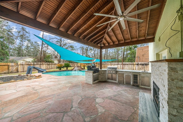view of patio featuring a gazebo, grilling area, a fenced backyard, and an outdoor kitchen