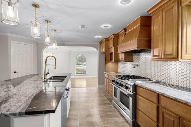 kitchen with tasteful backsplash, ornamental molding, double oven range, a sink, and premium range hood