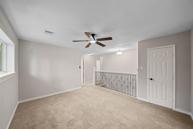 spare room with visible vents, ceiling fan, carpet floors, and baseboards