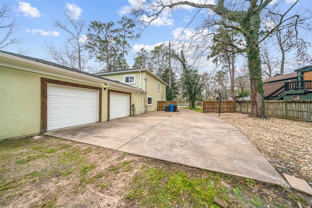view of home's exterior featuring concrete driveway, stucco siding, fence, and a garage
