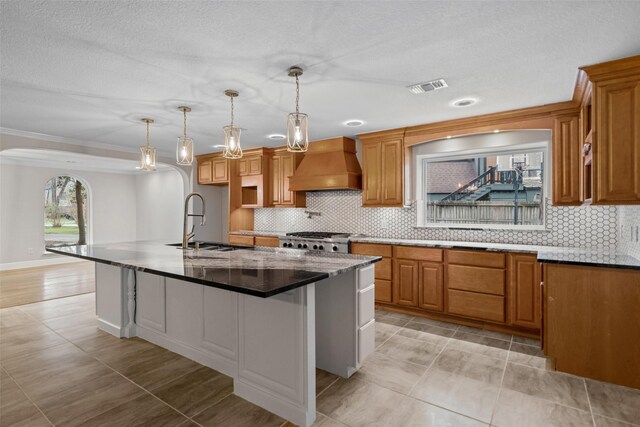 533 Rapidan Park, Conroe, TX 77302 - kitchen with custom exhaust hood, arched walkways, a sink, a kitchen island with sink, and crown molding