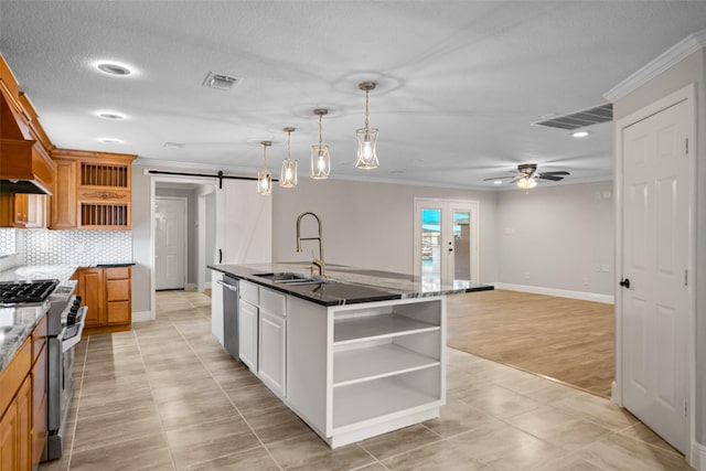 kitchen with crown molding, open shelves, a barn door, visible vents, and stainless steel appliances