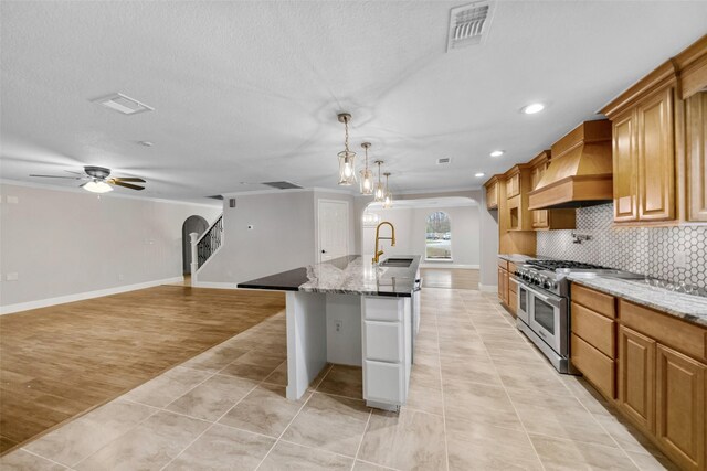 kitchen with premium range hood, backsplash, visible vents, arched walkways, and double oven range