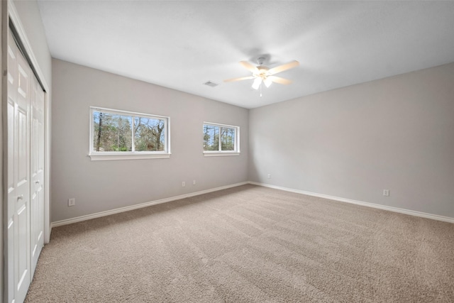 unfurnished bedroom featuring a closet, a ceiling fan, visible vents, carpet flooring, and baseboards
