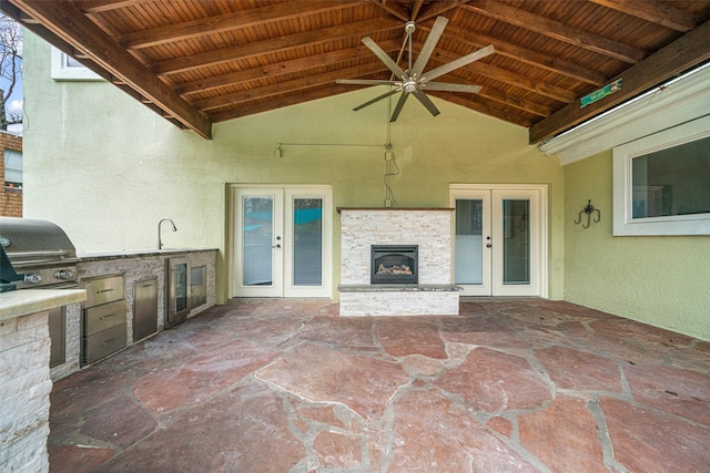 view of patio / terrace featuring exterior kitchen, an outdoor stone fireplace, french doors, area for grilling, and ceiling fan