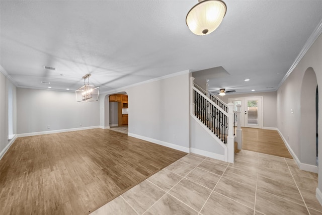interior space with arched walkways, stairway, ceiling fan with notable chandelier, and ornamental molding