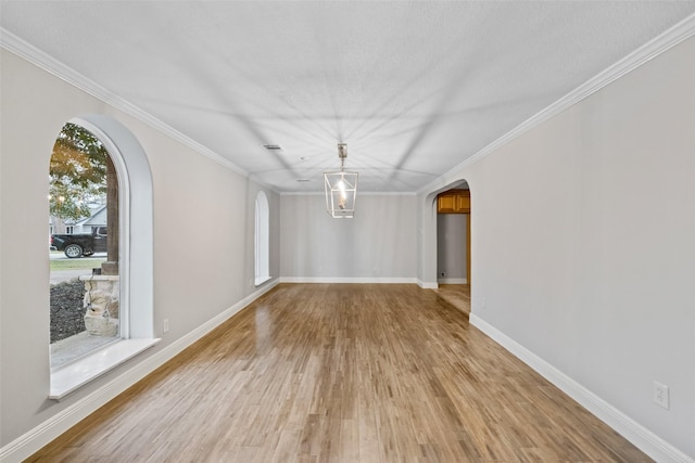 unfurnished dining area with arched walkways, light wood-style floors, and baseboards