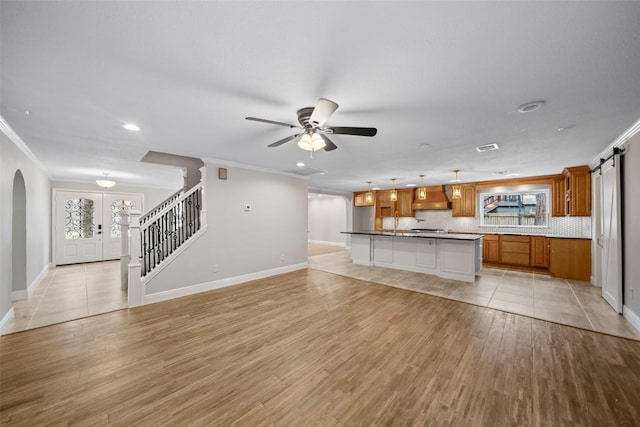 unfurnished living room with arched walkways, stairway, crown molding, and a ceiling fan