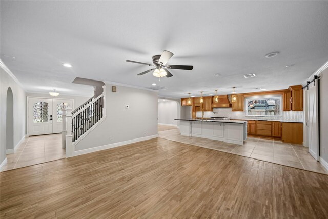 533 Rapidan Park, Conroe, TX 77302 - unfurnished living room with arched walkways, crown molding, stairway, a ceiling fan, and light wood finished floors