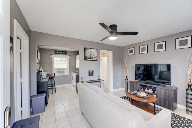 living room with light tile patterned floors, baseboards, and a ceiling fan