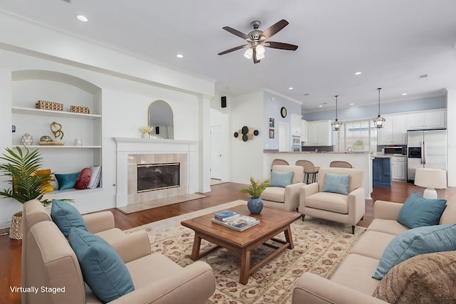 living area with crown molding, wood finished floors, and ceiling fan