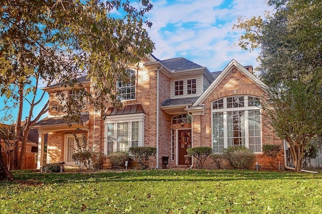 traditional-style home with fence, a front lawn, and brick siding