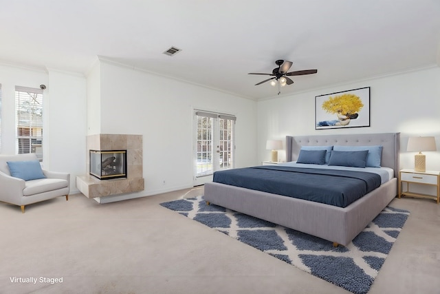 carpeted bedroom with crown molding, a fireplace, multiple windows, and visible vents
