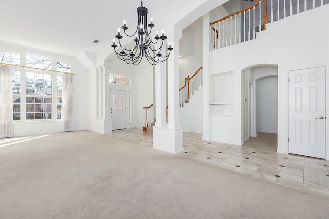 unfurnished dining area with arched walkways, a high ceiling, an inviting chandelier, stairway, and carpet flooring