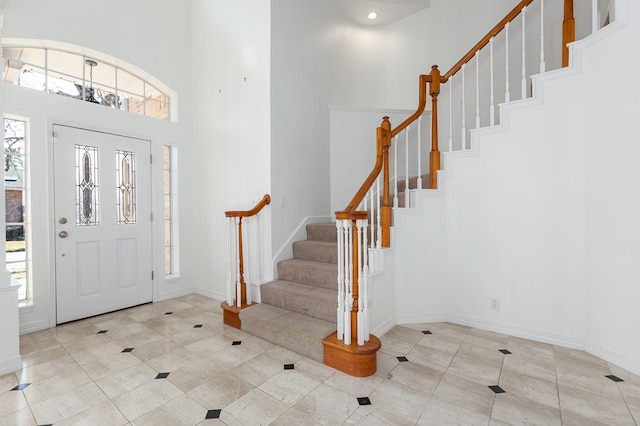 foyer with a high ceiling, baseboards, tile patterned flooring, and stairway