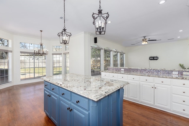 kitchen featuring dark wood finished floors, blue cabinetry, plenty of natural light, and ceiling fan with notable chandelier