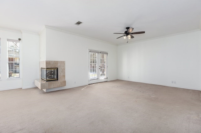 unfurnished living room with a wealth of natural light, visible vents, ornamental molding, and ceiling fan