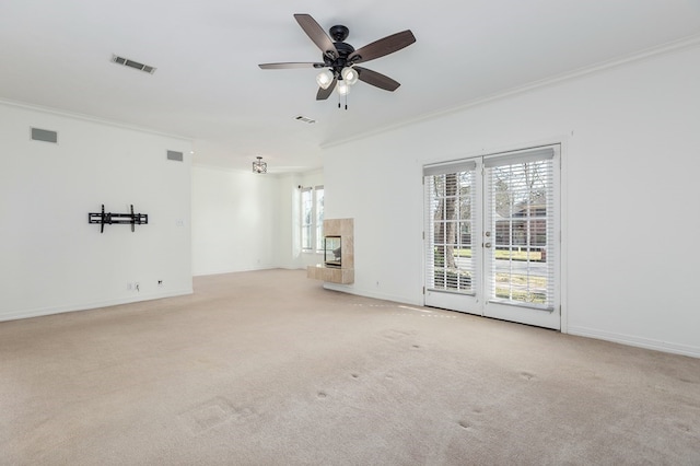 empty room featuring crown molding, a fireplace, light carpet, and visible vents