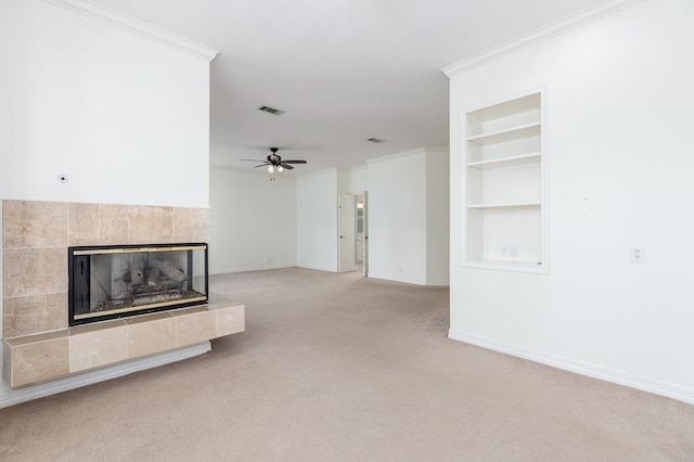 unfurnished living room with baseboards, built in features, a ceiling fan, crown molding, and light colored carpet