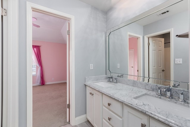 bathroom featuring baseboards, double vanity, a sink, and visible vents