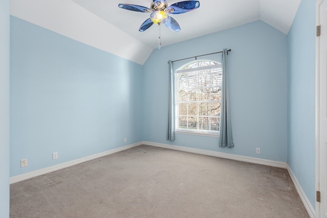 carpeted empty room featuring ceiling fan, vaulted ceiling, and baseboards